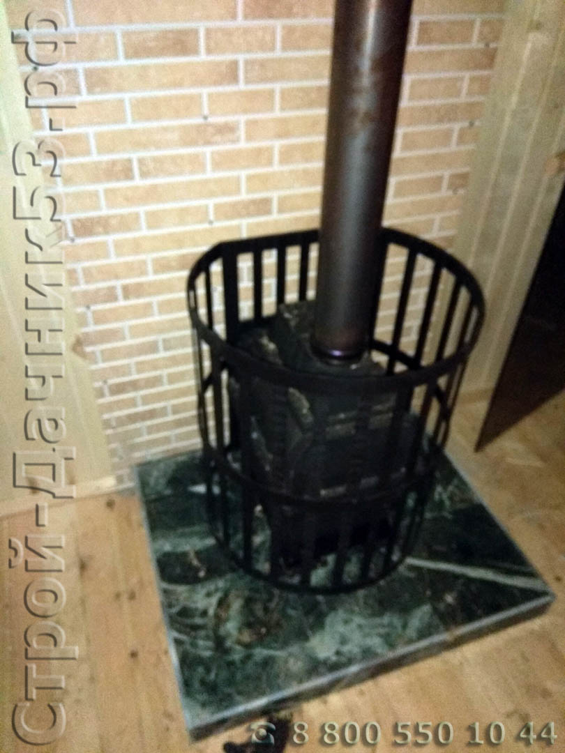 Установленная печь с каменкой и фальш панелью под кирпич изолирующую стену от дымохода