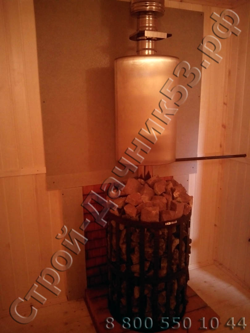 Вид установленной печи в парной с баком для горячей воды на дымоходе