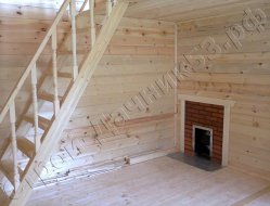 Гостинная комната брусовой бани, с выходом печи с облицовочным экраном и лестнечным пролетом